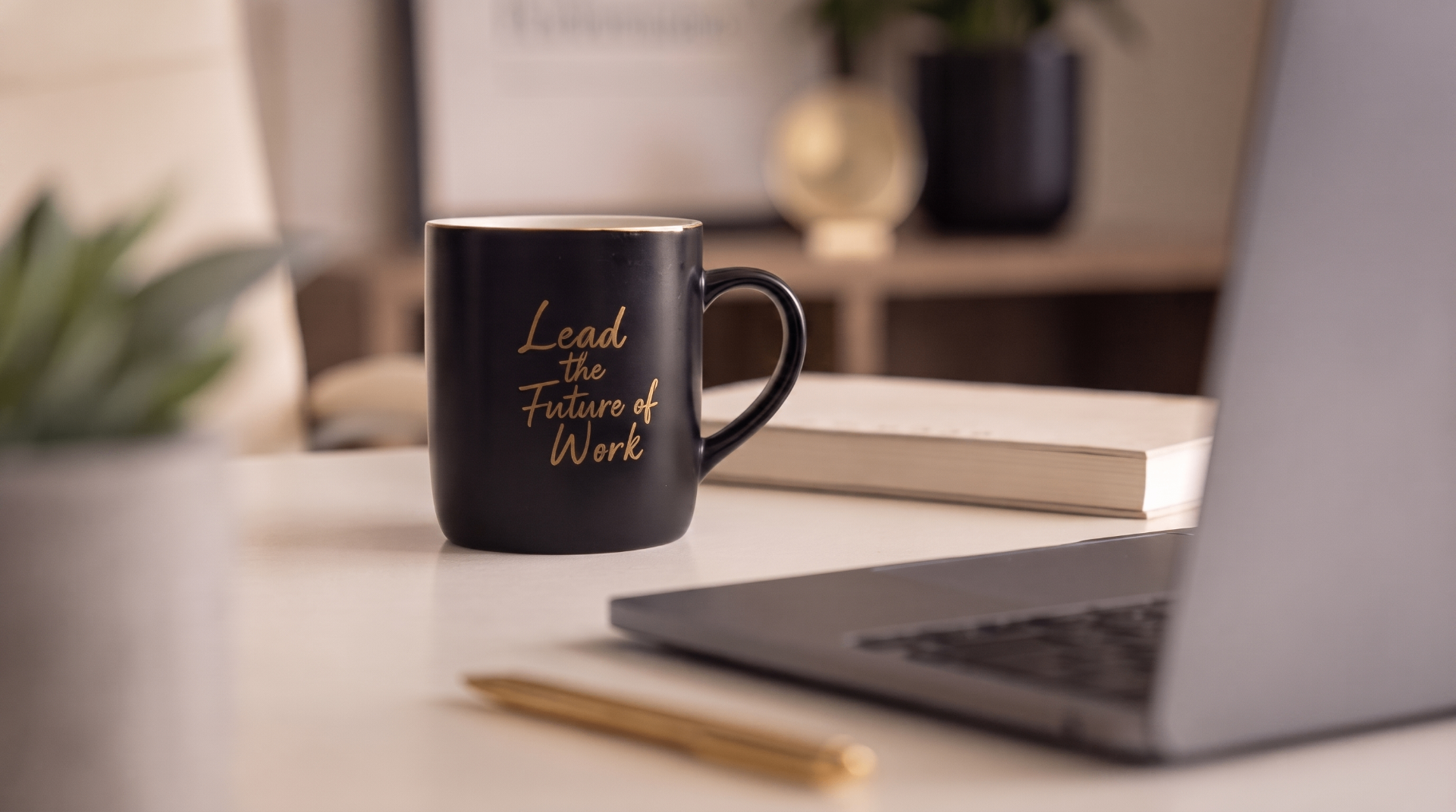 Black mug reading 'Lead the Future of Work' beside a laptop and notebook